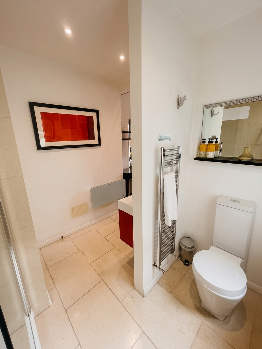 Hastings House Bedroom 1 ensuite — limestone tiles, chrome heated towel rail and Wild England toiletries