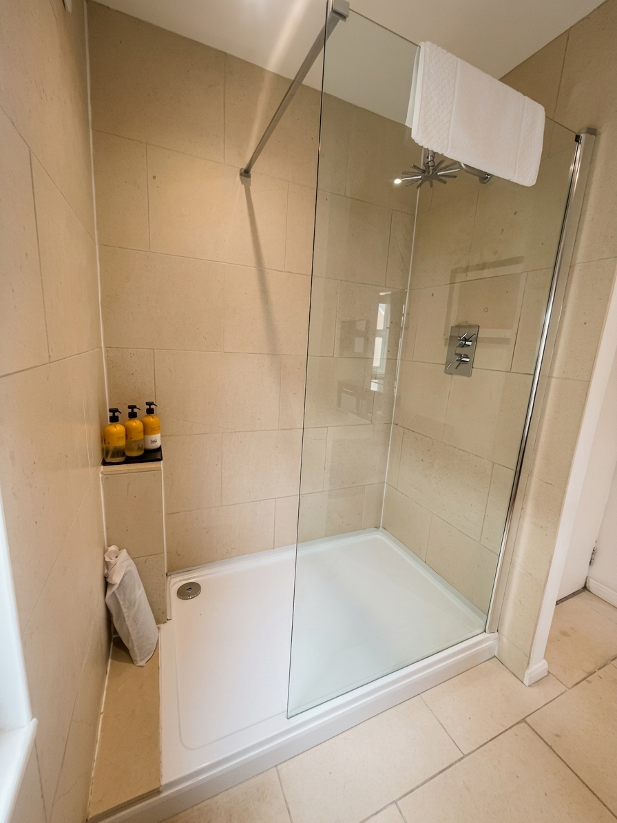 Hastings House Bedroom 1 ensuite — walk-in shower with limestone tiles and Wild England products