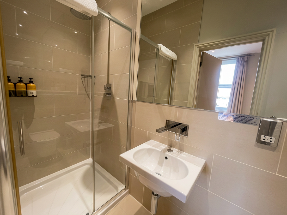 Hastings House Bedroom 4 ensuite — shower enclosure with rain head and neutral tiles
