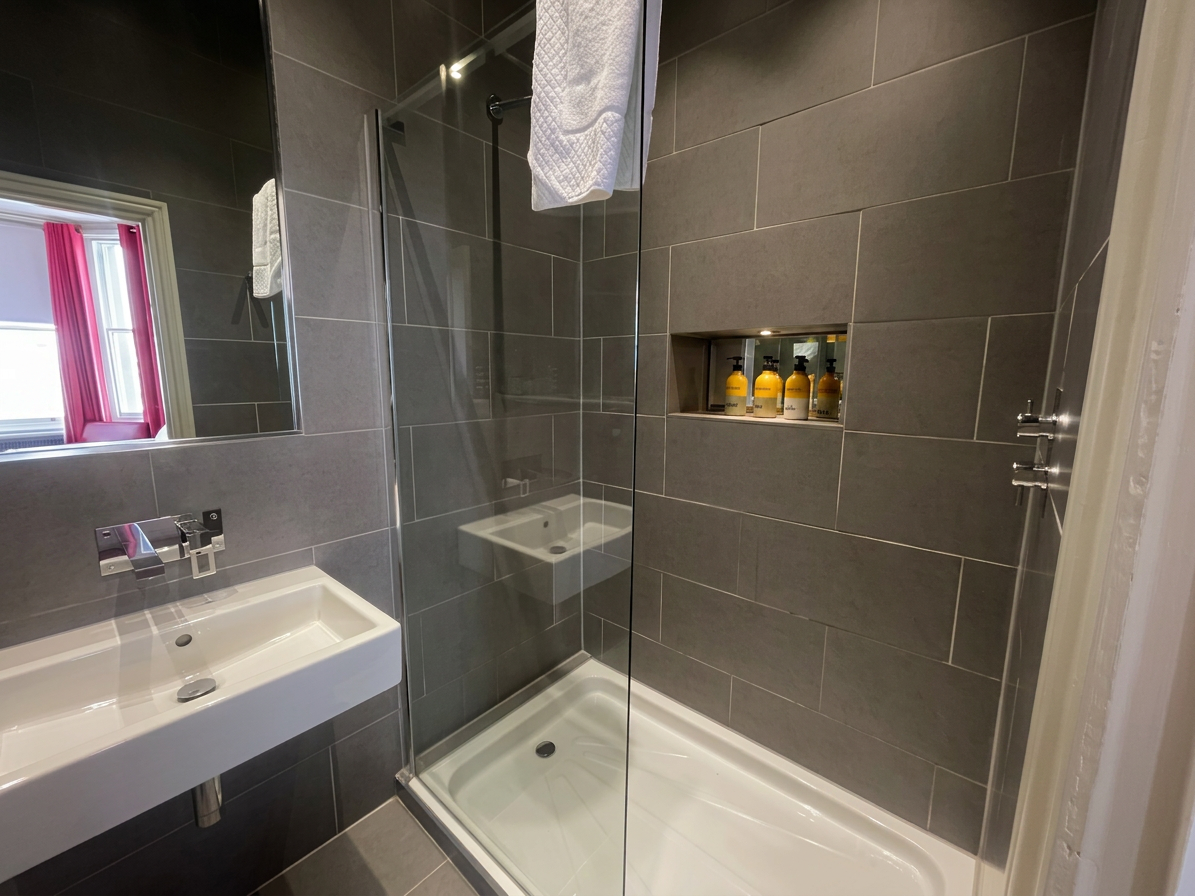 Hastings House Bedroom 7 ensuite — dark grey tiled shower with Wild England toiletries