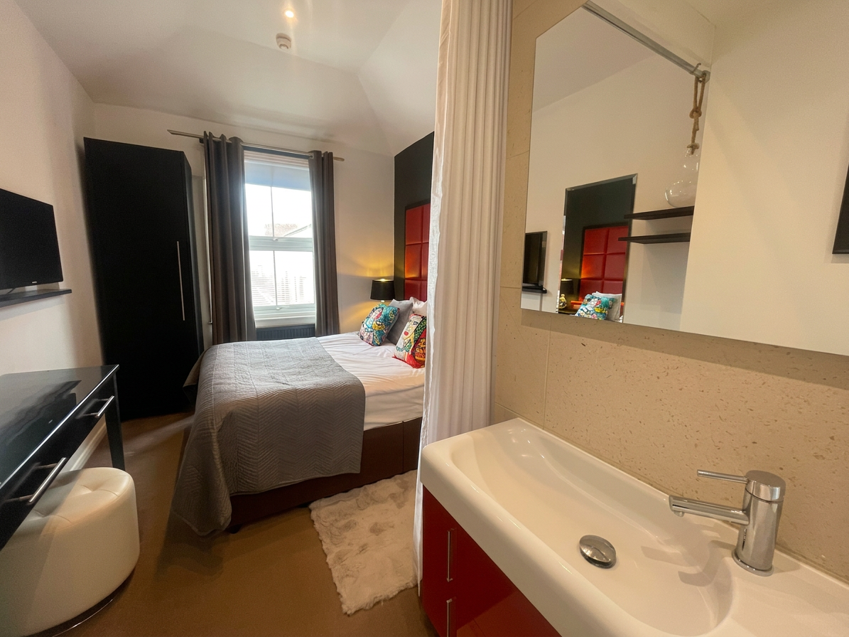 Hastings House Bedroom 1 — ensuite basin and view to bed