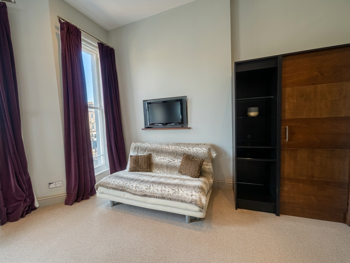 Hastings House Bedroom 3 — sofa area with smart TV and walnut wardrobe