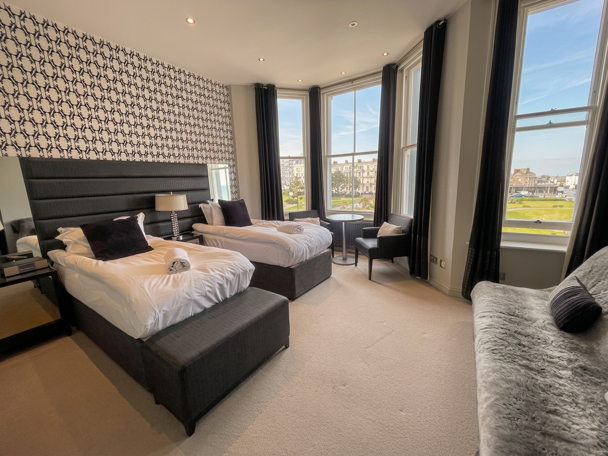 Hastings House Bedroom 5 — black and white graphic wallpaper, charcoal headboard and sea views