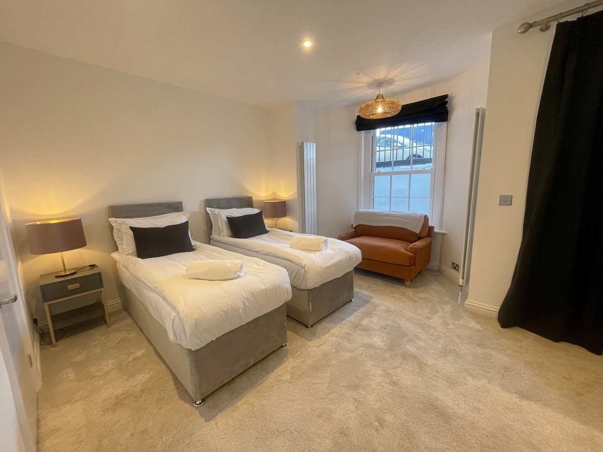 Hastings House Bedroom 8 — twin beds with warm pendant light, leather armchair and wicker lamp