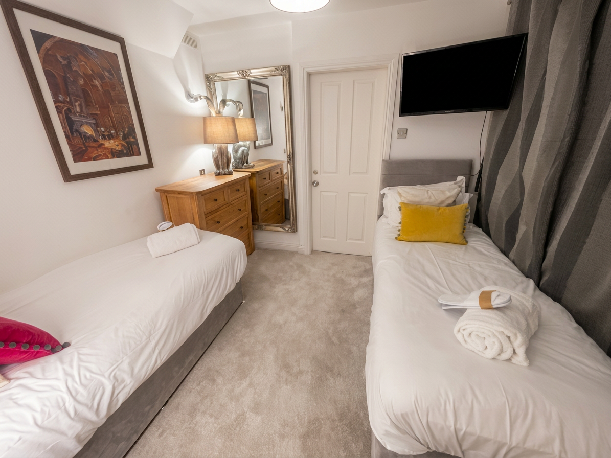 Hastings House Bedroom 9 — twin beds with yellow cushions, smart TV and character artwork