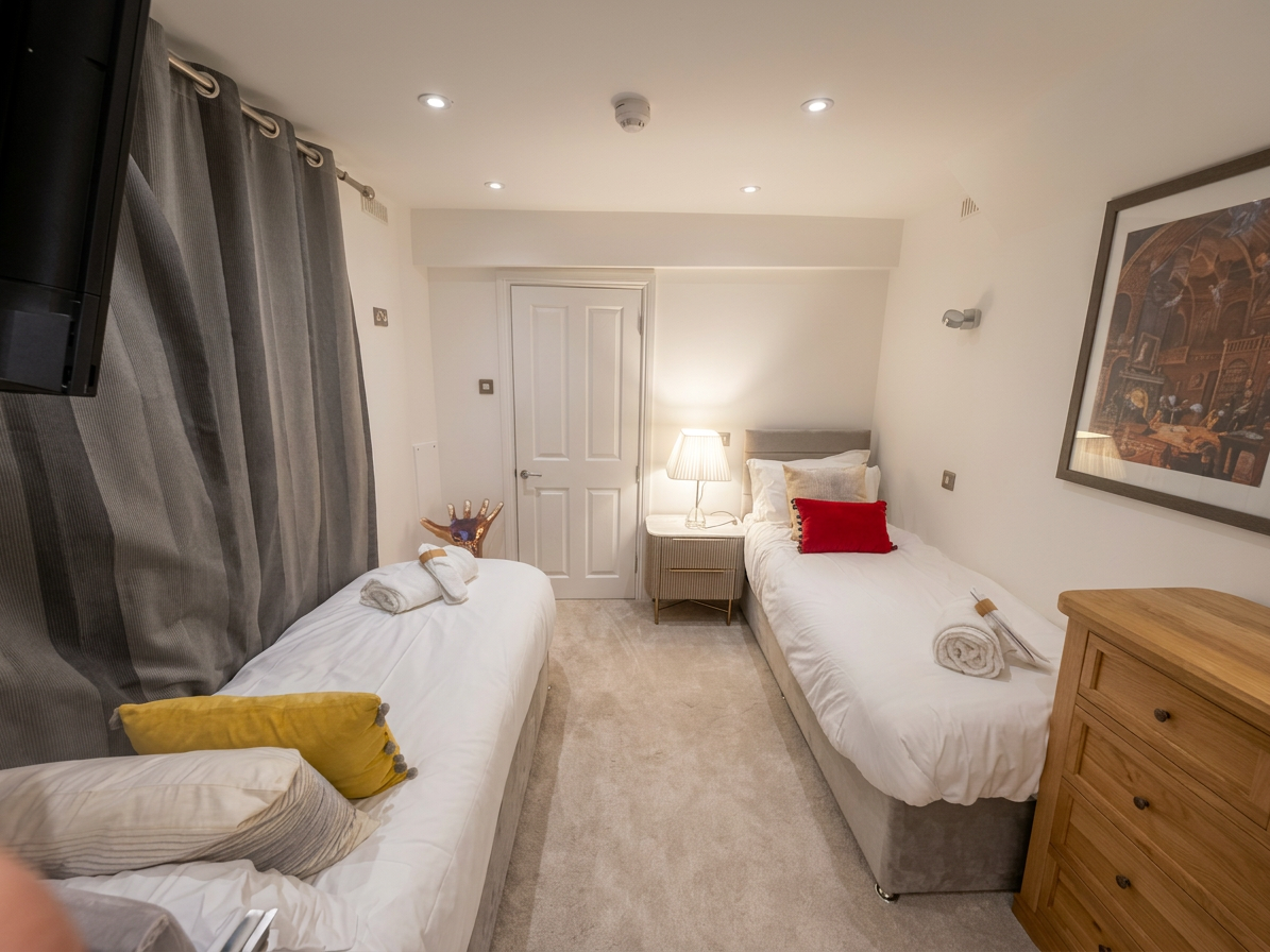 Hastings House Bedroom 9 — twin beds from foot showing smart TV and character artwork