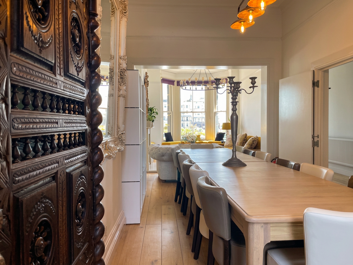 Hastings House dining room — carved antique dresser, long table and view through to the sea-view lounge