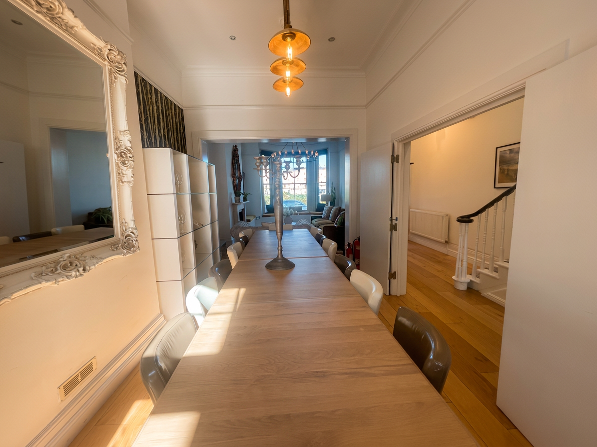 Hastings House long dining table with pendant light, white ornate mirror and view through to lounge